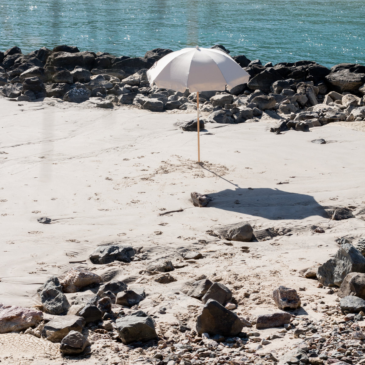 Dunes Splice Beach Umbrella beside clear water and coastal rocks
