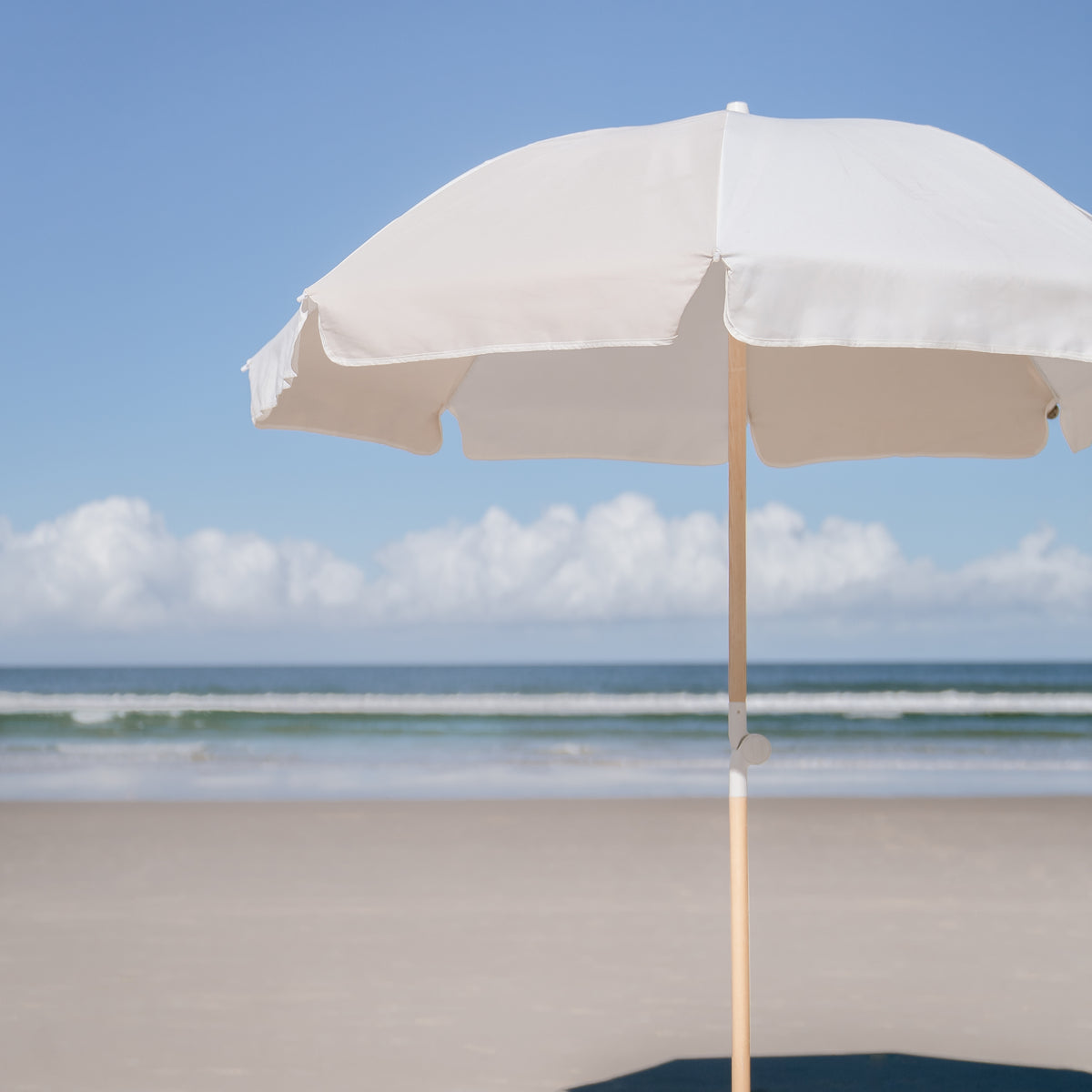 Dunes Splice Beach Umbrella with sand and off-white panels beside the shoreline