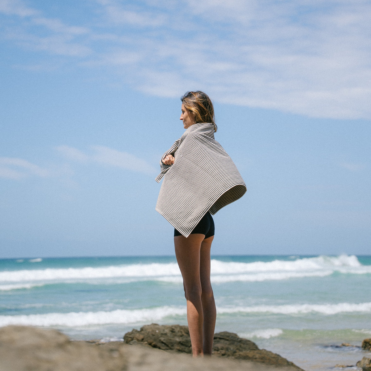 Black striped beach towel wrapped around a model's shoulders.